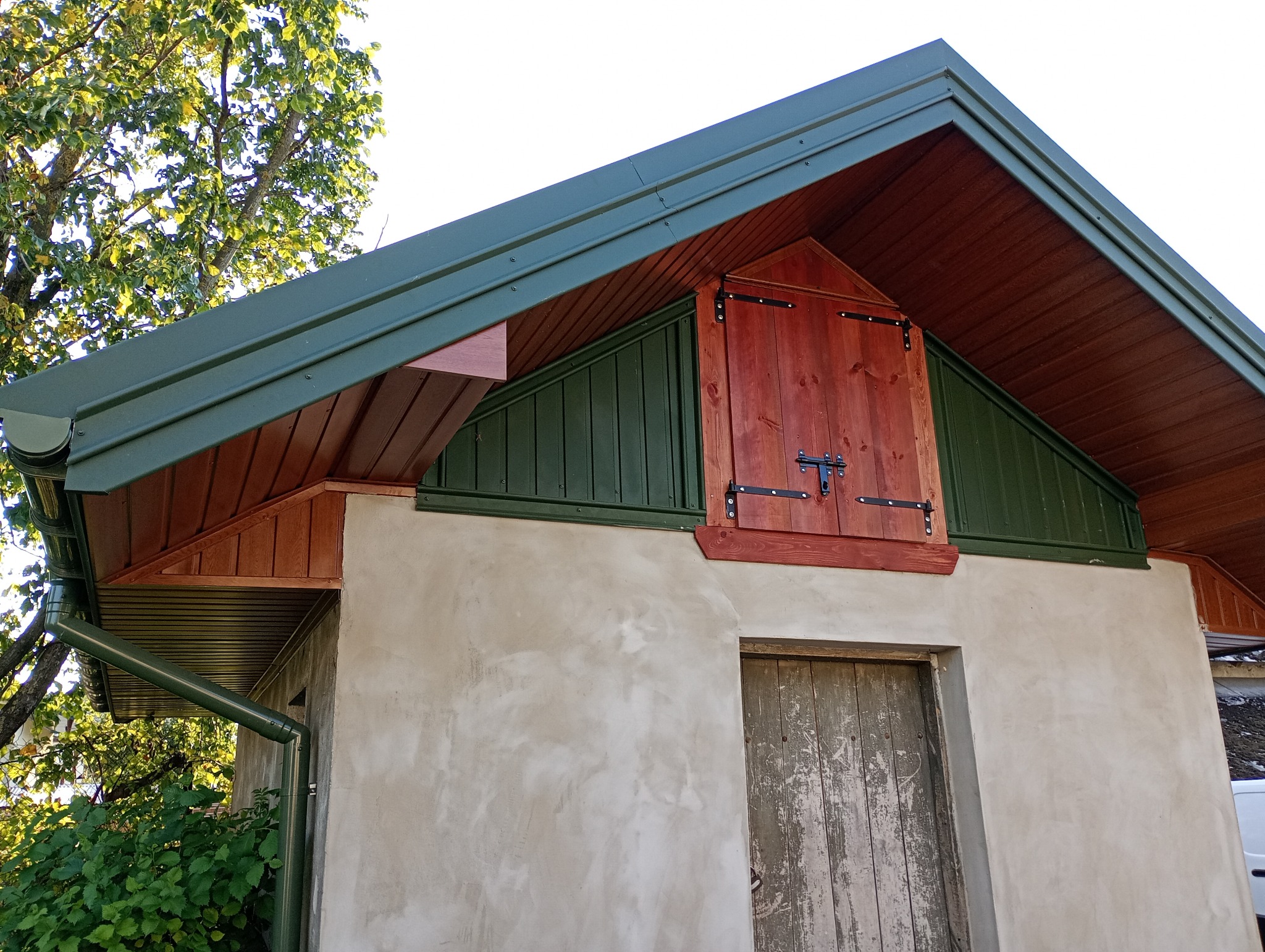 Zakończona obróbka blacharska dachu z rynnami w Ulan-Majorat. Widoczna drewniana zabudowa lukarny i zielona blacha. Detal wykończenia.