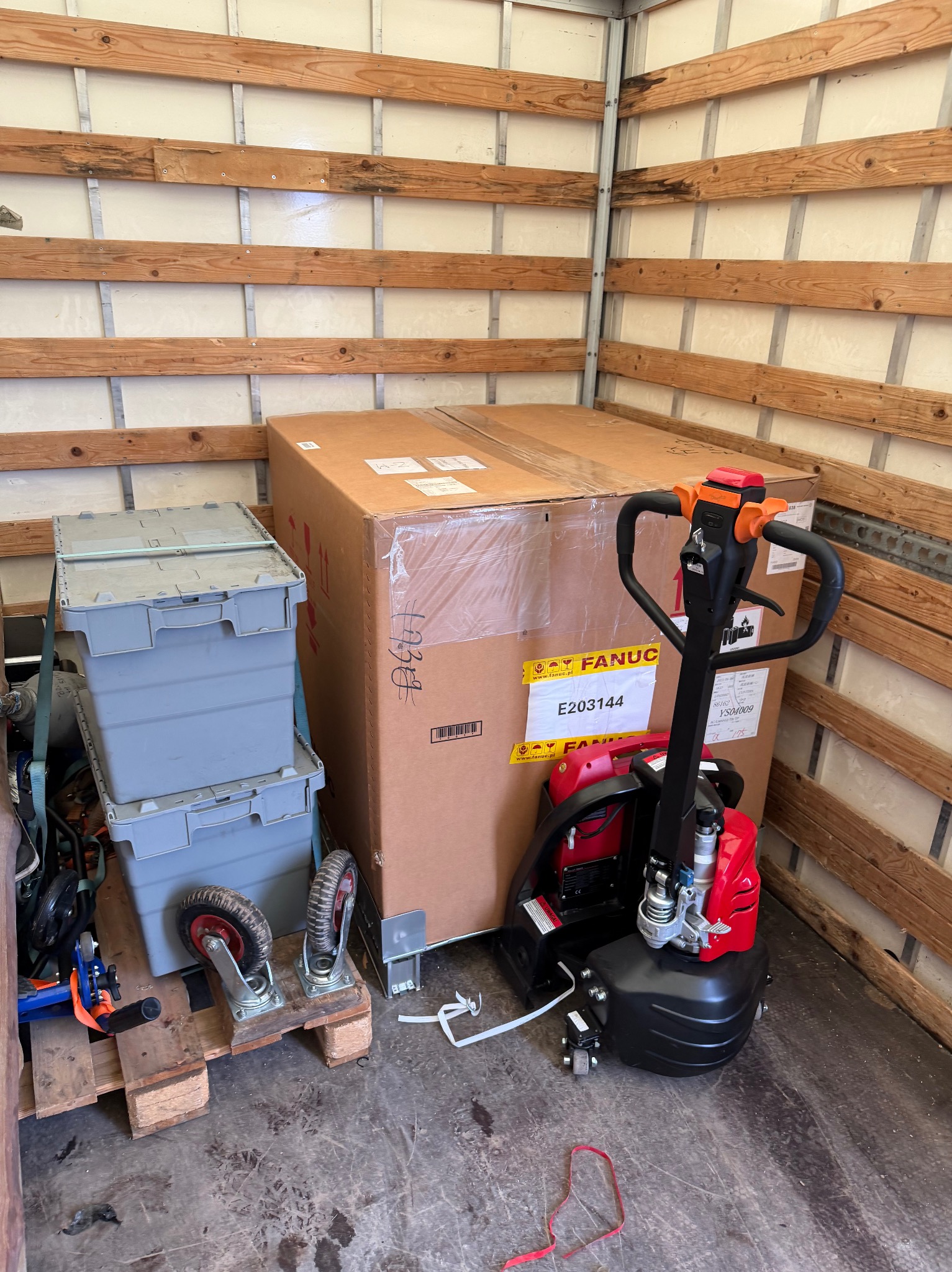 Wnętrze furgonetki: karton Fanuc, paleciak elektryczny, skrzynki na palecie. Przygotowanie do transportu, zabezpieczenie ładunku.