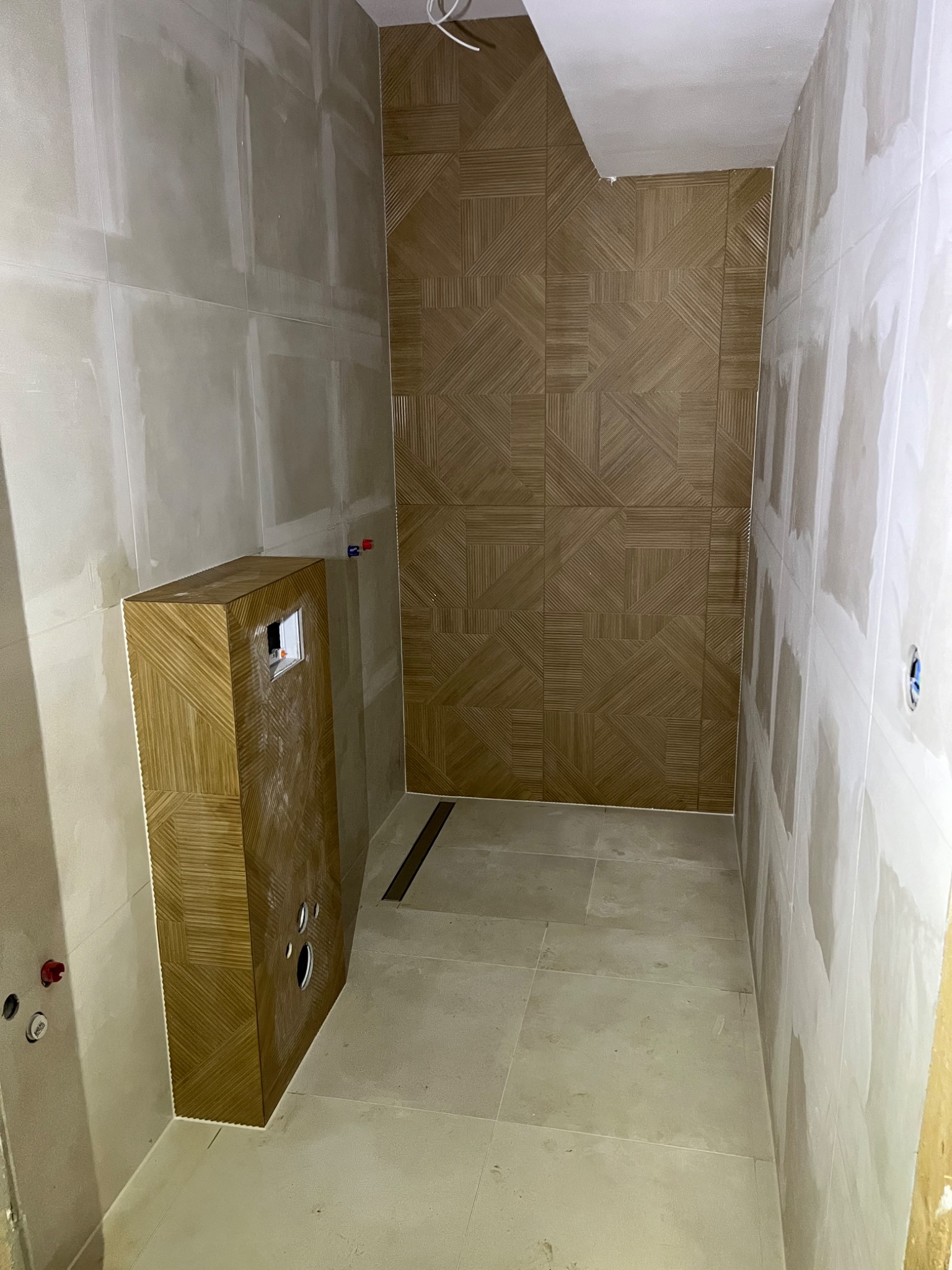 Łazienka w trakcie wykończenia: ściany przygotowane pod płytki, zabudowa WC z dekoracyjną okładziną, widoczna instalacja. Etap prac wykończeniowych.