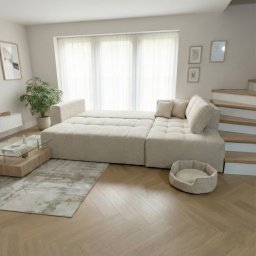 LUNVERO SPÓŁKA Z OGRANICZONĄ ODPOWIEDZIALNOŚCIĄ - Jasny, modułowy narożnik z puszystej tkaniny w salonie z drewnianą podłogą w jodełkę, obok schodów i legowiska dla psa, w tle okno z białymi zasłonami.