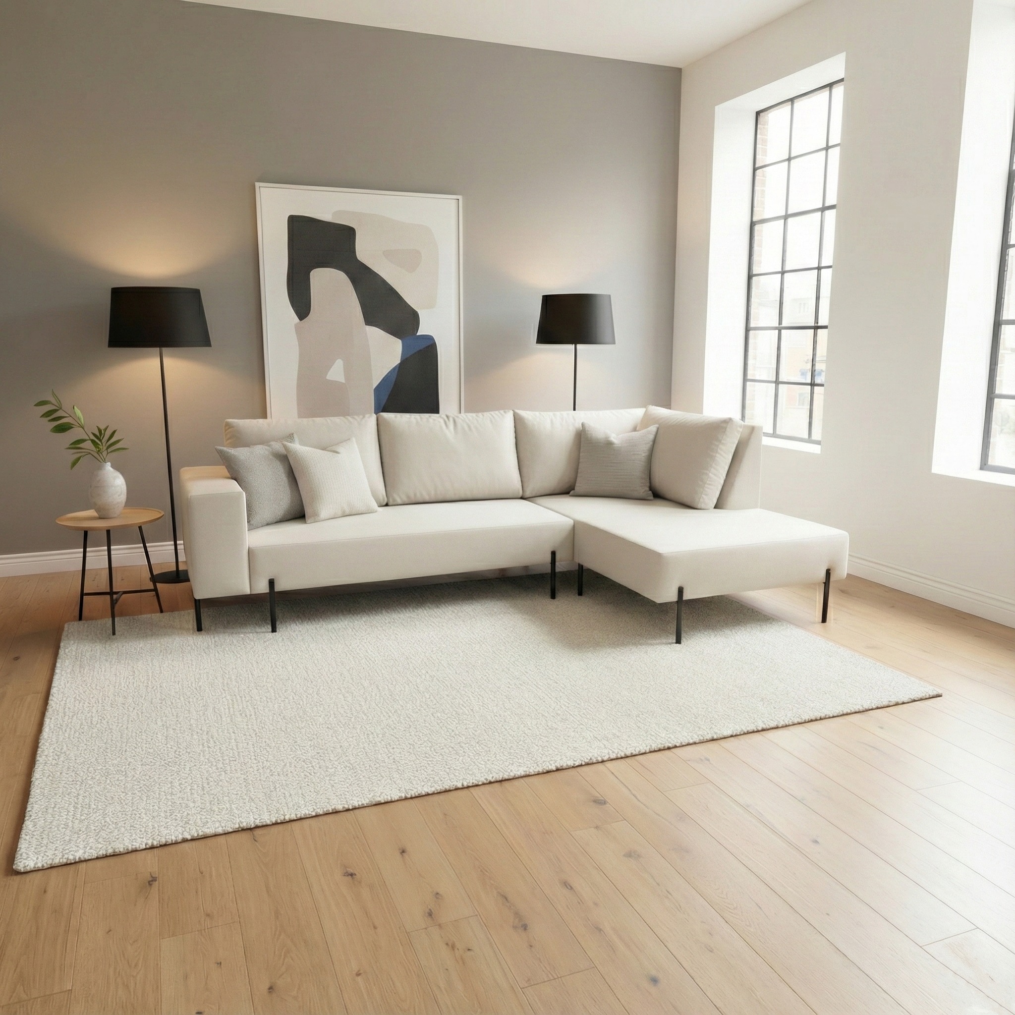 Jasny narożnik z poduszkami na kremowym dywanie w salonie z drewnianą podłogą i dużymi oknami. Minimalistyczny design z lampami podłogowymi i abstrakcyjnym obrazem.