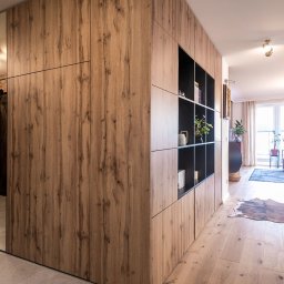 TREEO ART BARTŁOMIEJ STOKŁOSA, SEBASTIAN RZEPECKI S.C. - Drewniana szafa wnękowa z lustrzanymi drzwiami i otwartymi półkami, w jasnym wnętrzu z drewnianą podłogą i widokiem na salon.