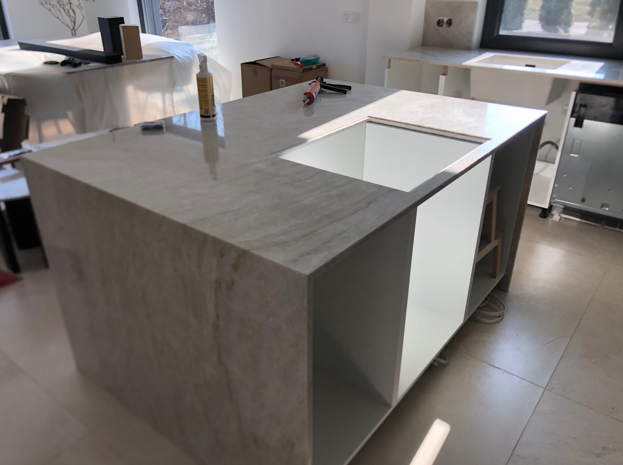 Montaż blatu kuchennego z wycięciem na zlew. Widoczne narzędzia i materiały montażowe. Jasna kolorystyka wnętrza, naturalne światło.