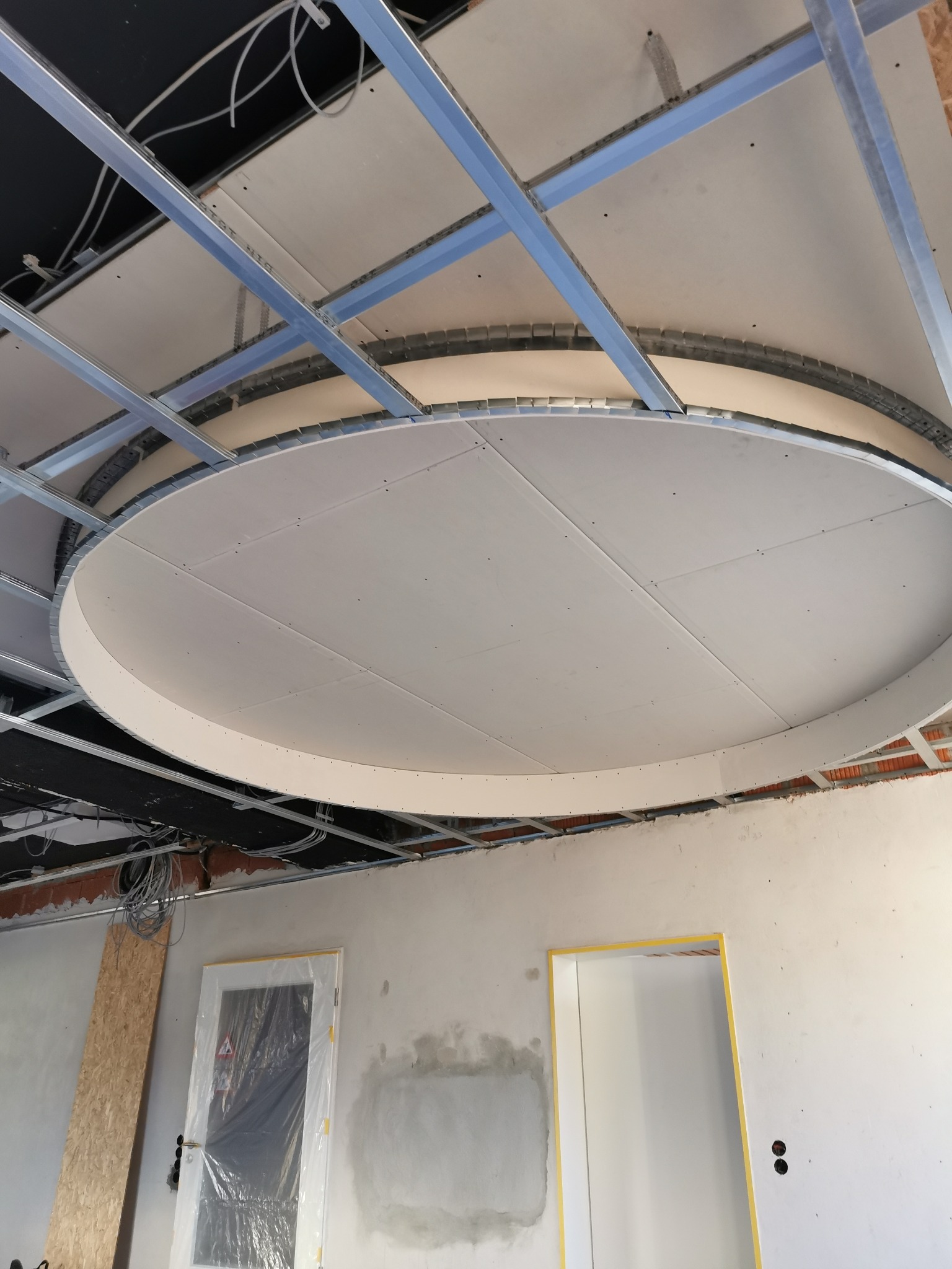 Okrągła konstrukcja sufitu podwieszanego z płyt gipsowo-kartonowych na metalowym stelażu, widok z dołu, Spytkowice.