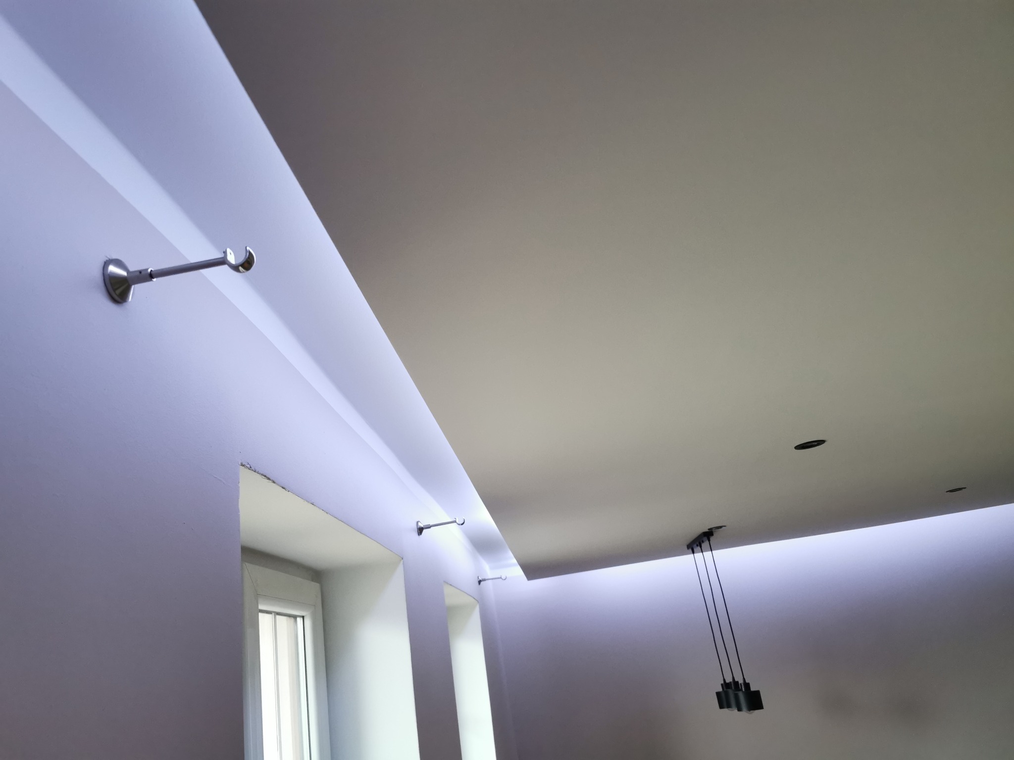 Wykończony sufit podwieszany z oświetleniem LED i karniszami, widok z dołu. Minimalistyczny design, gładkie powierzchnie, nowoczesne lampy wiszące.