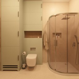 Pracownia projektowania wnętrz Olga Kucharzewska - Kompaktowa łazienka w odcieniach beżu i zieleni z kabiną prysznicową, toaletą i wysoką szafką. Na ścianie dekoracyjny wzór liści. Minimalistyczny design.