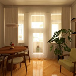 Jasny salon z drewnianym stołem, krzesłami i zielonym fotelem. Na ścianie grafika, a obok okna duża monstera. Parkiet w jodełkę i ciepłe oświetlenie.