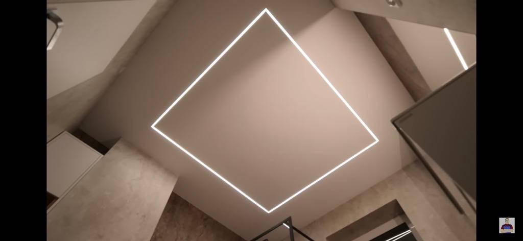 Nowoczesna łazienka z podświetlanym kwadratem na suficie, beżowe ściany, minimalistyczny design. Ujęcie z dołu podkreśla geometryczny kształt oświetlenia.