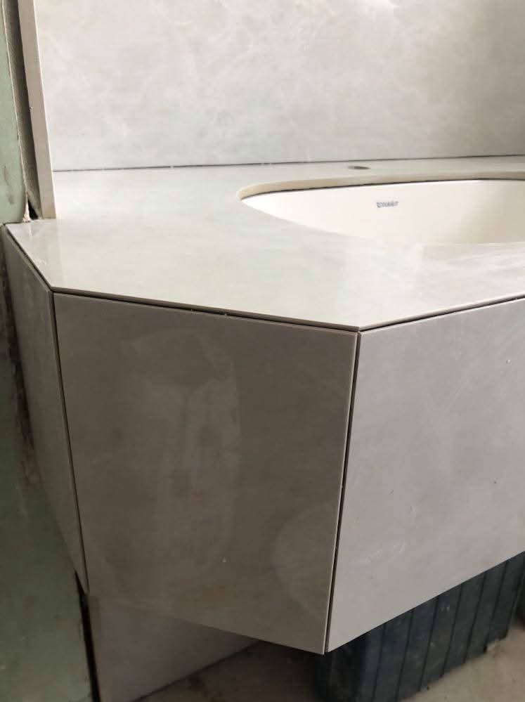 Wykończona umywalka z blatem i obudową z płytek ceramicznych w łazience. Widoczne precyzyjne łączenia płytek i minimalistyczny design.