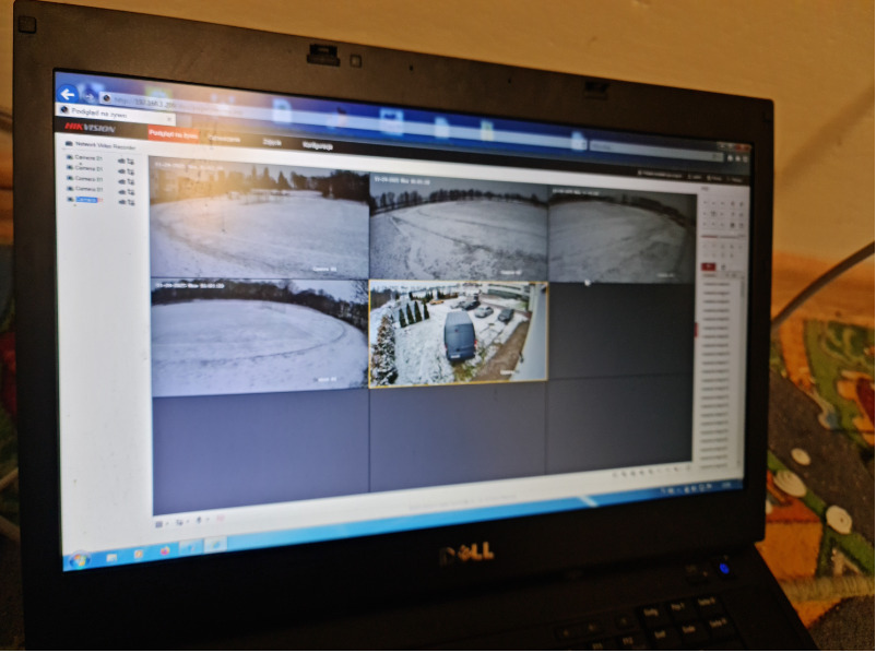 Ekran laptopa Dell z widokiem z kamer monitoringu Hikvision, prezentujący zimowy krajobraz i zaparkowane pojazdy. Widok z kilku kamer na jednym ekranie.