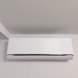 Klimatyzacja w Krakowie Maciej Kowalczyk - Biały klimatyzator marki Gree zamontowany na jasnej ścianie w pomieszczeniu. Widoczny fragment sufitu i narożnika ściany. Minimalistyczny design.