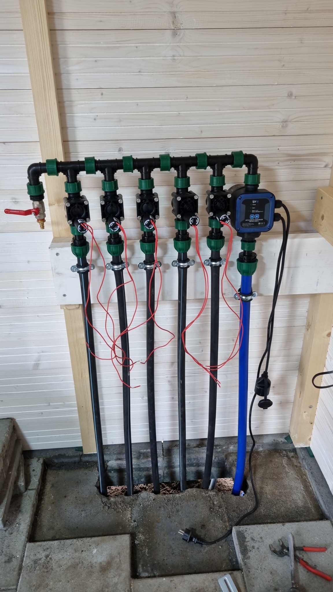 System nawadniania z rurami i sterownikiem, zamontowany w pomieszczeniu w Witnicy. Widoczne czarne rury, czerwone przewody i niebieska rura.