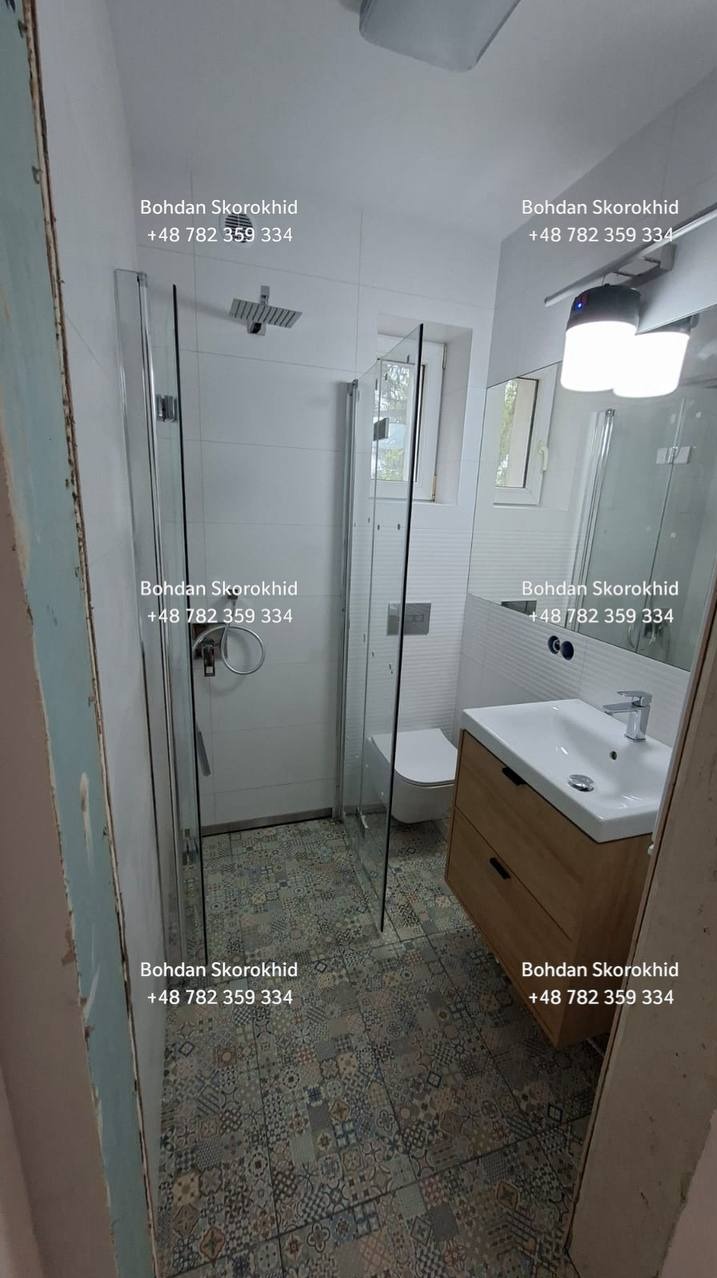 Nowoczesna łazienka po remoncie: kabina prysznicowa ze szklanymi drzwiami, umywalka z szafką z jasnego drewna, wzorzysta podłoga. Minimalistyczny design.