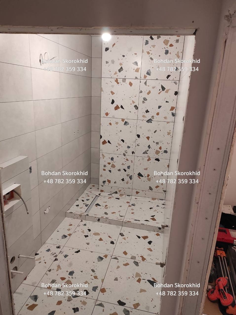 Wykończona łazienka z nowoczesnymi płytkami lastryko na ścianach i podłodze. Widoczny odpływ liniowy w strefie prysznica i białe płytki w pozostałej części łazienki.