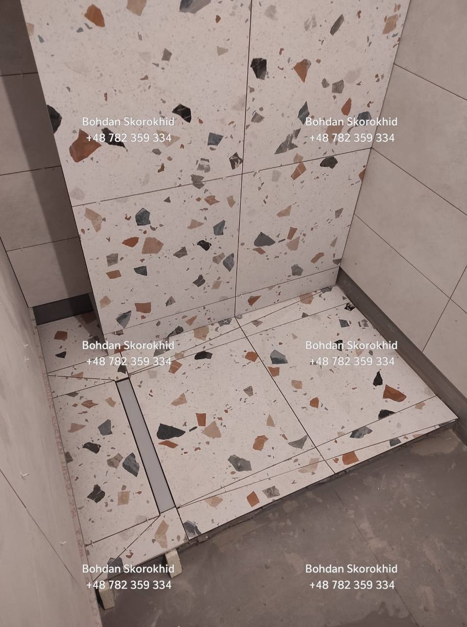 Ukończona łazienka z terazzo, widoczny odpływ liniowy. Jasne płytki z kolorowymi fragmentami tworzą nowoczesny wzór. Minimalistyczny design i precyzyjne wykonanie.