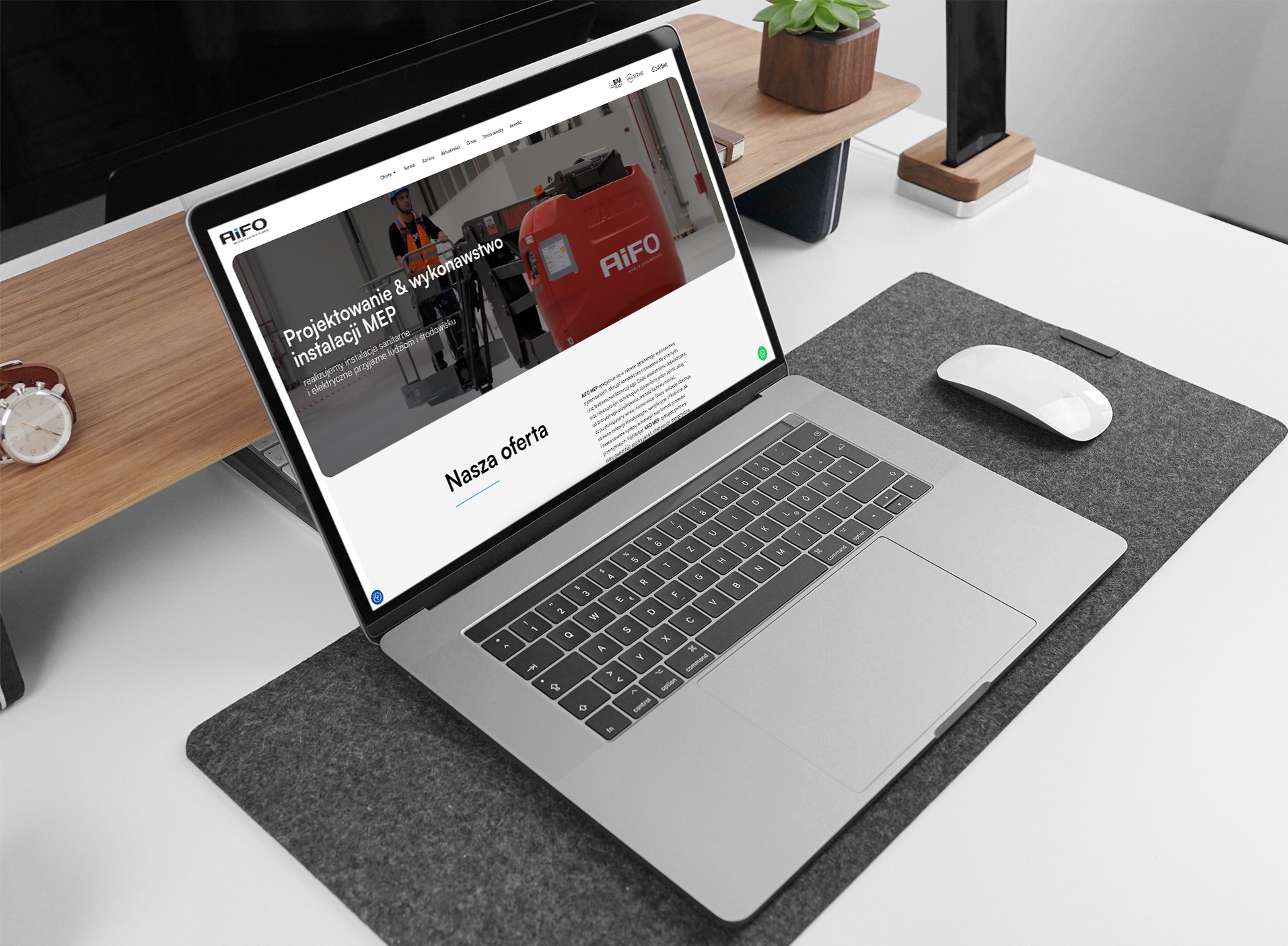 Laptop wyświetla stronę internetową firmy AiFO z ofertą projektowania i wykonawstwa instalacji MEP. Widoczna myszka, podkładka i elementy biurka w tle.