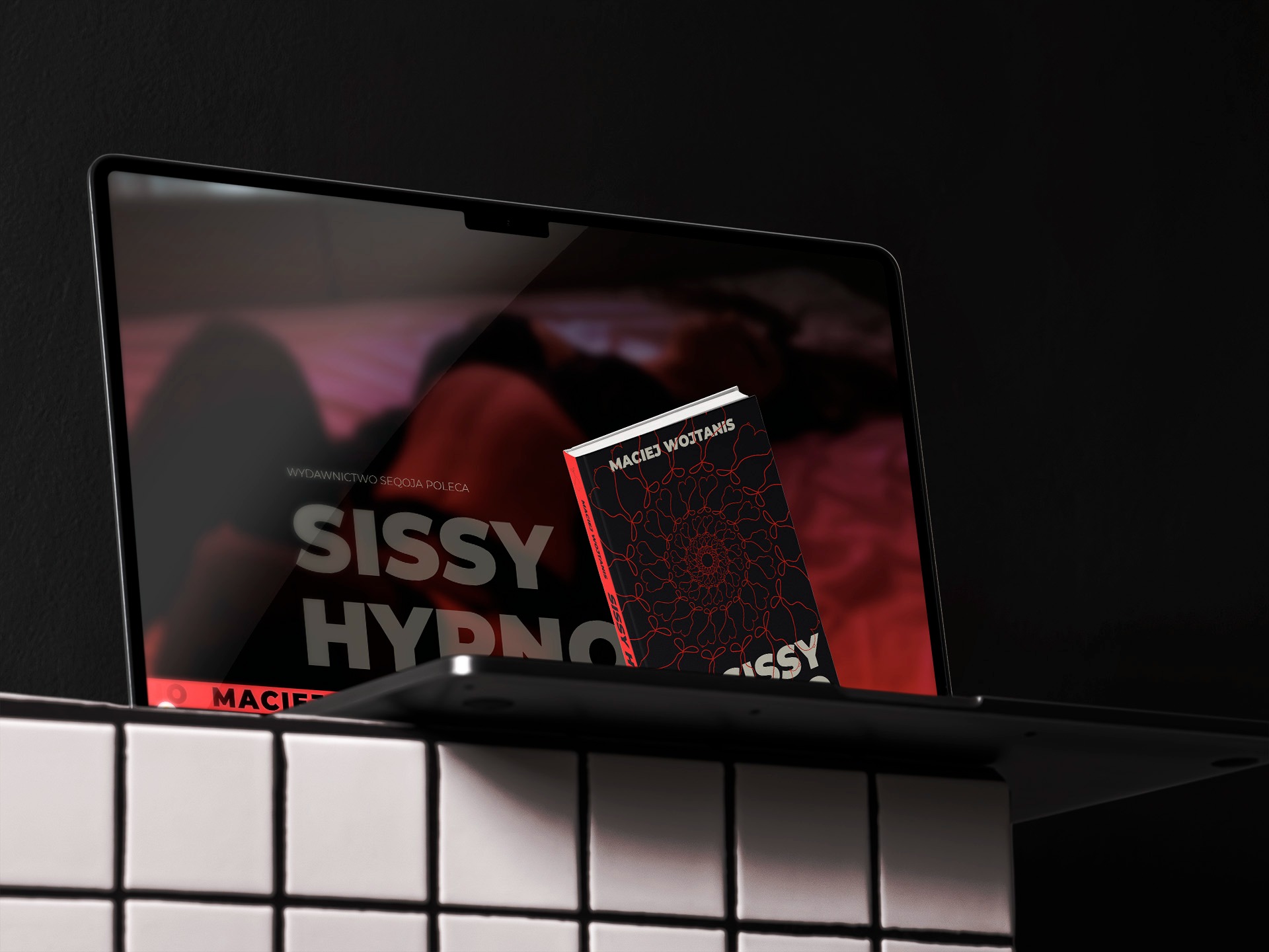 Laptop wyświetla okładkę książki 'Sissy Hypno' Macieja Wojtanisa, stojącej obok na białych płytkach. Ciemne tło, minimalistyczny design.