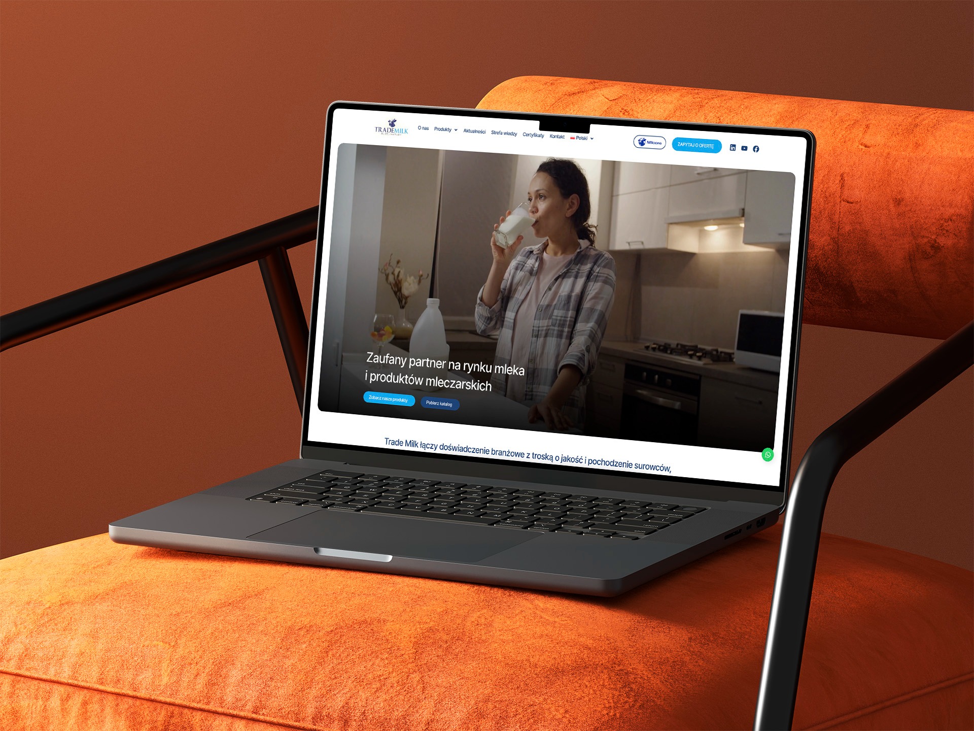Laptop na pomarańczowym fotelu prezentuje stronę internetową Trade Milk z kobietą pijącą mleko w tle kuchni. Minimalistyczny design, czcionki czytelne, nawigacja intuicyjna.