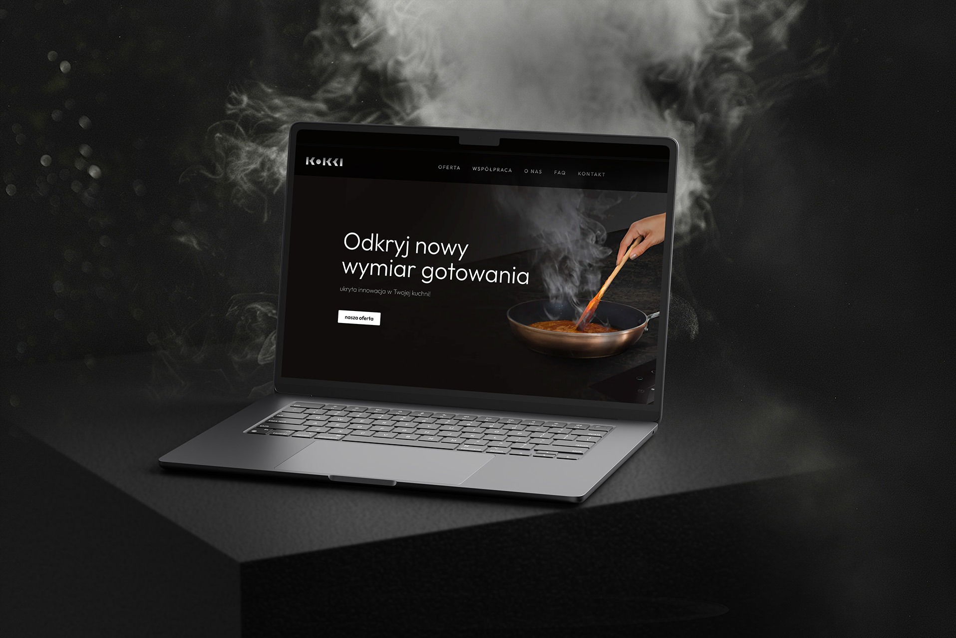 Laptop prezentuje stronę internetową z motywem gotowania, gdzie dłoń miesza potrawę na patelni. Minimalistyczny design, ciemne tło, subtelne oświetlenie.