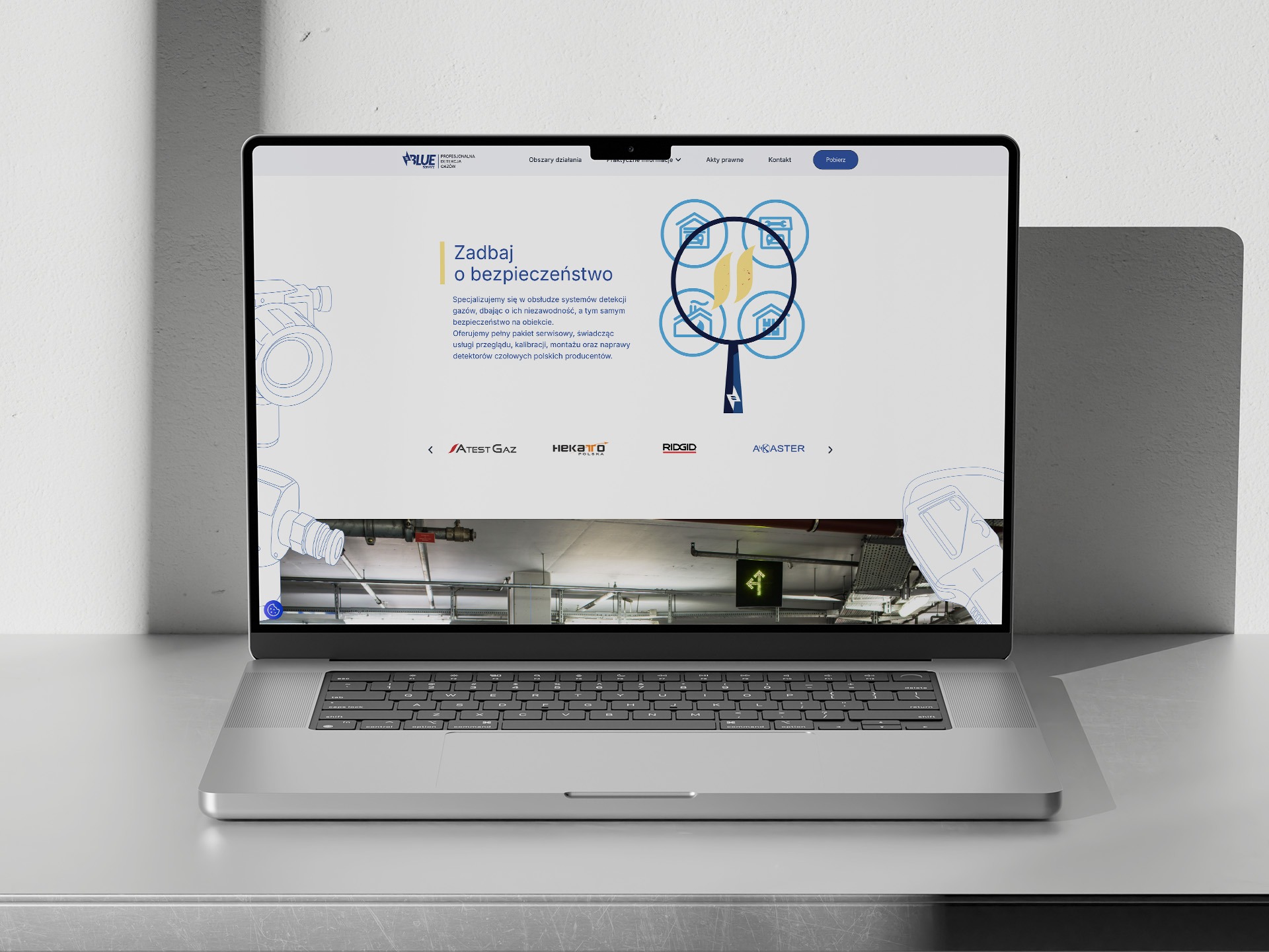 Laptop prezentuje stronę internetową firmy z branży detekcji gazów, z logo i hasłem 'Zadbaj o bezpieczeństwo'. Widoczne elementy interfejsu i grafiki związane z bezpieczeństwem.