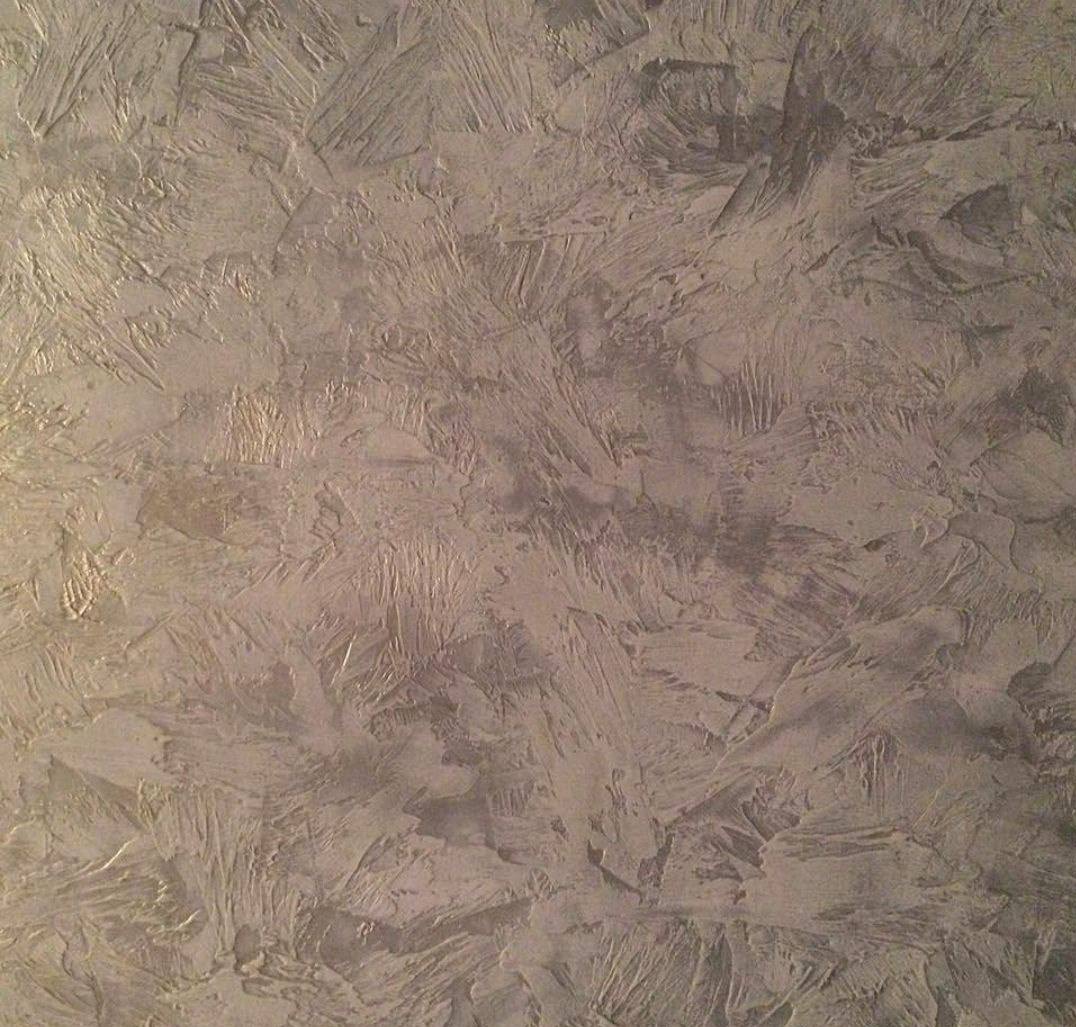 Szara ściana z dekoracyjną fakturą, przypominającą pociągnięcia pędzlem. Nieregularna powierzchnia z subtelnymi refleksami światła.