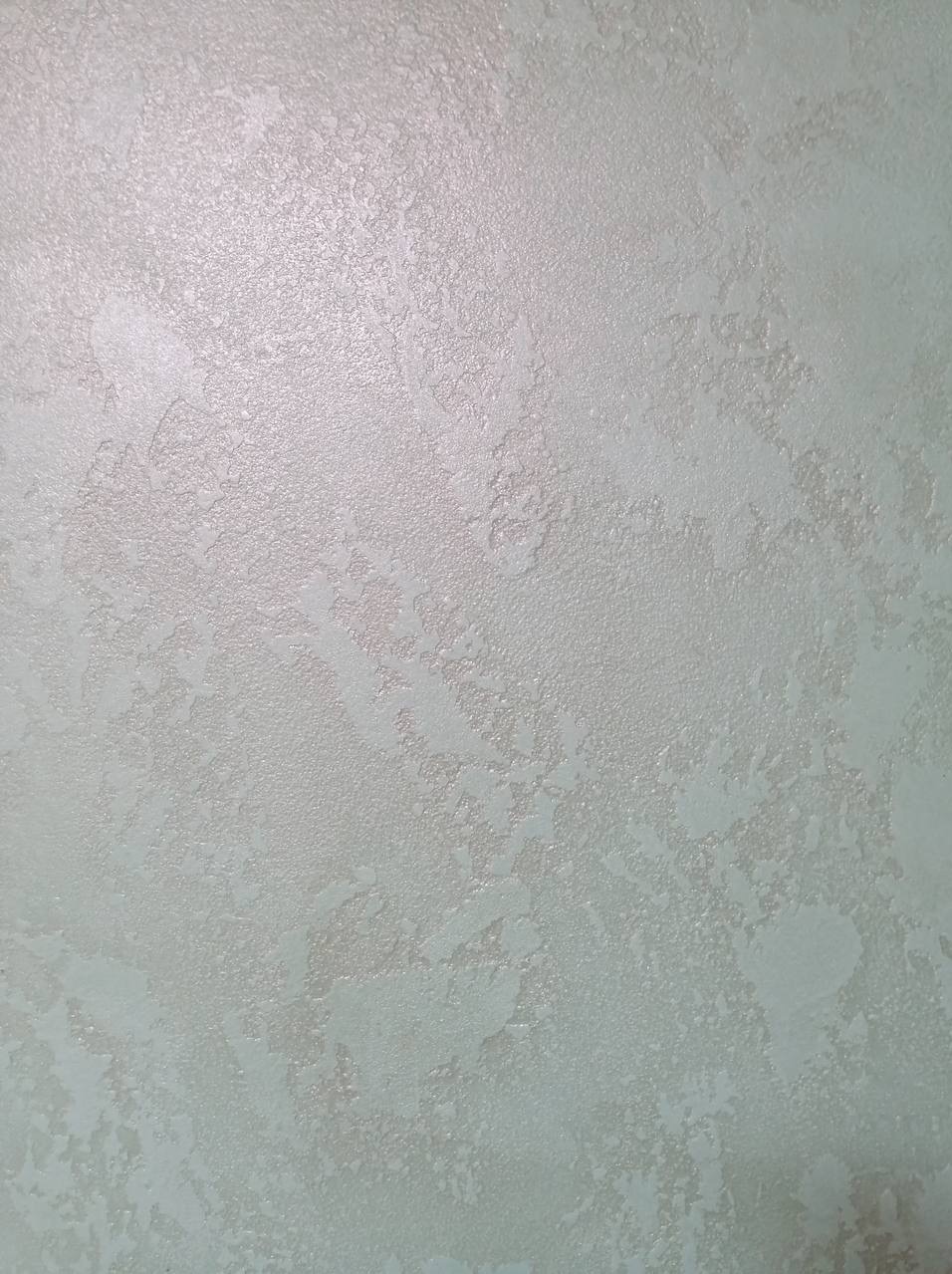 Delikatna, strukturalna ściana w odcieniach bieli i szarości, z subtelnym połyskiem, ukazująca unikalną fakturę dekoracyjną.