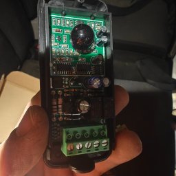 Dron Elektro - Otwarty pilot do bramy z widoczną elektroniką, zieloną płytką drukowaną i złączami śrubowymi, trzymany w dłoni. Widoczne elementy elektroniczne.