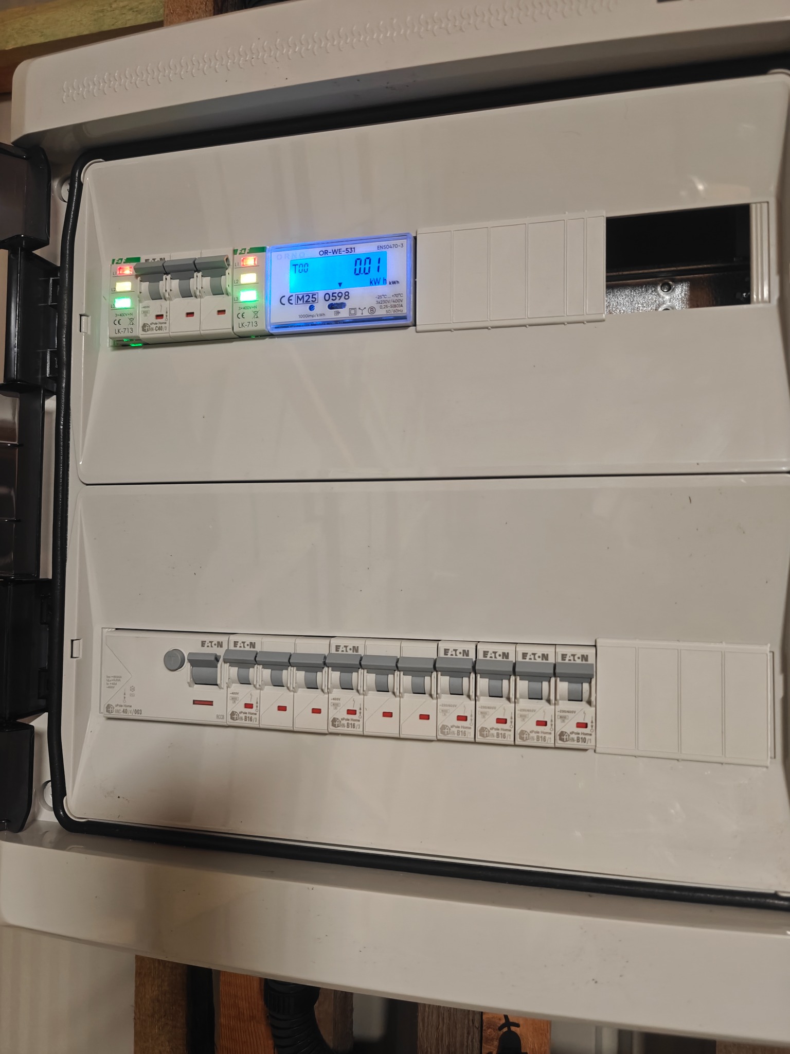 Rozdzielnica elektryczna z bezpiecznikami i licznikiem energii, widok z bliska. Elementy instalacji elektrycznej wewnątrz obudowy.