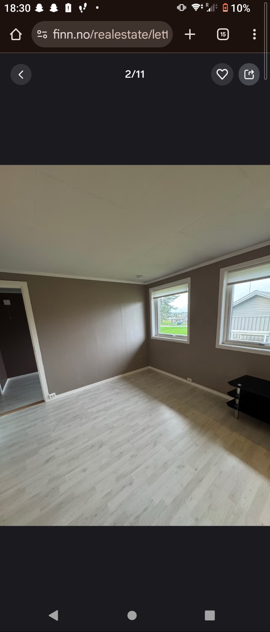 Jasne panele podłogowe w pokoju z brązowymi ścianami i dwoma oknami. Widok na zewnątrz przez okna. Minimalistyczny wystrój wnętrza.