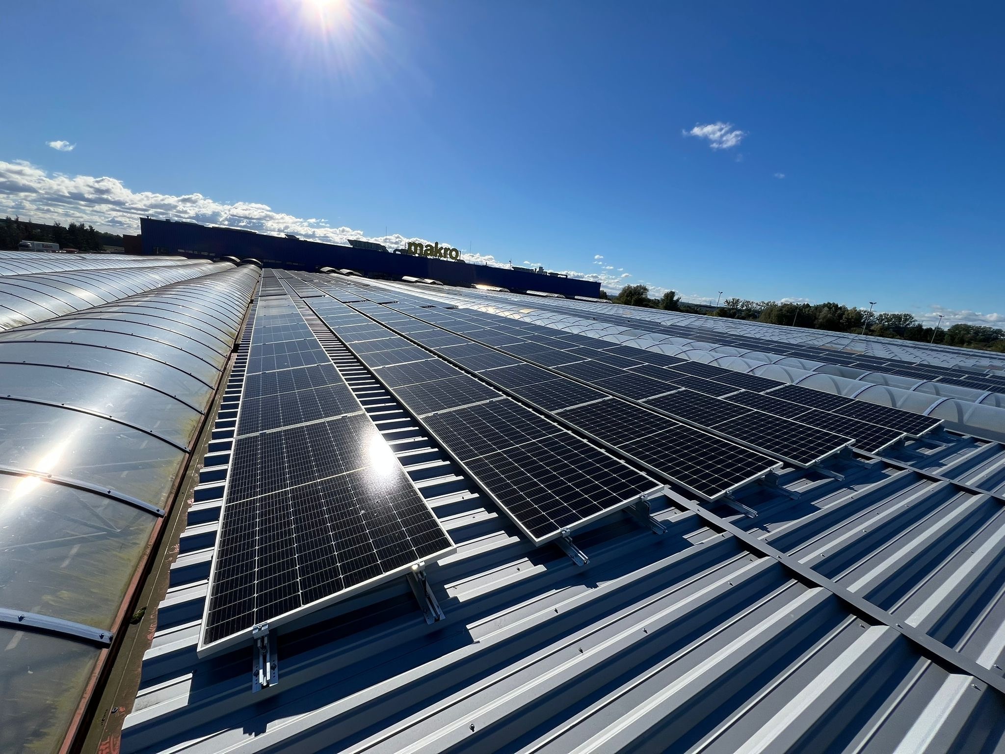 Instalacja fotowoltaiczna na dachu budynku Makro w Bydgoszczy, widok z góry w słoneczny dzień. Panele zamontowane na metalowej konstrukcji.