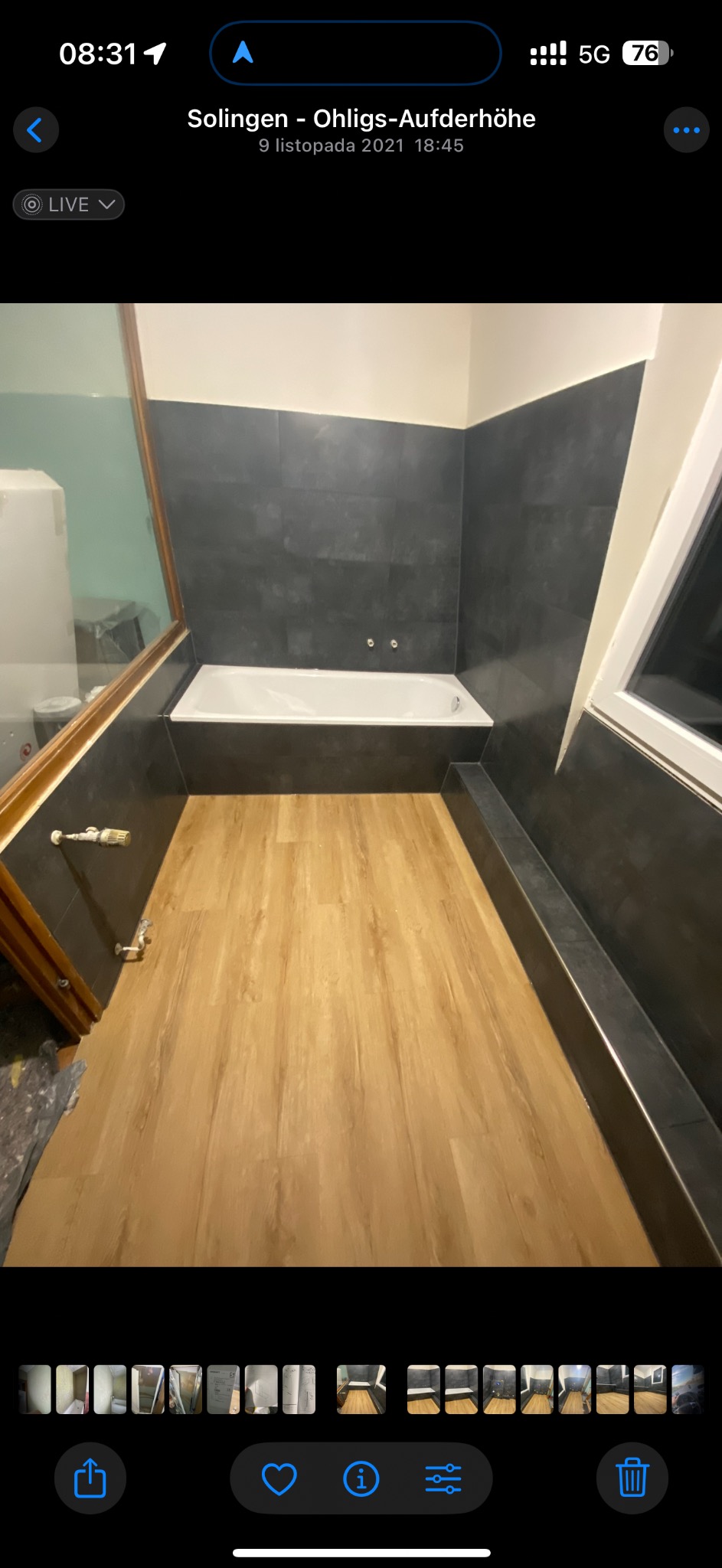 Nowoczesna łazienka po remoncie: drewnopodobna podłoga, ciemne płytki na ścianach, biała wanna. Minimalistyczny design, widok z góry, ukończone wykończenie.