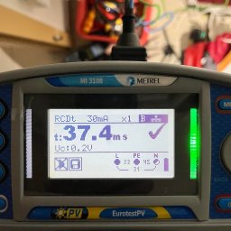 Aleks Shlosar - Miernik Metrel MI 3108 EurotestPV z wyświetlonym wynikiem pomiaru RCDt 37.4ms, używany podczas pomiarów elektrycznych. W tle widoczna skrzynka narzędziowa.