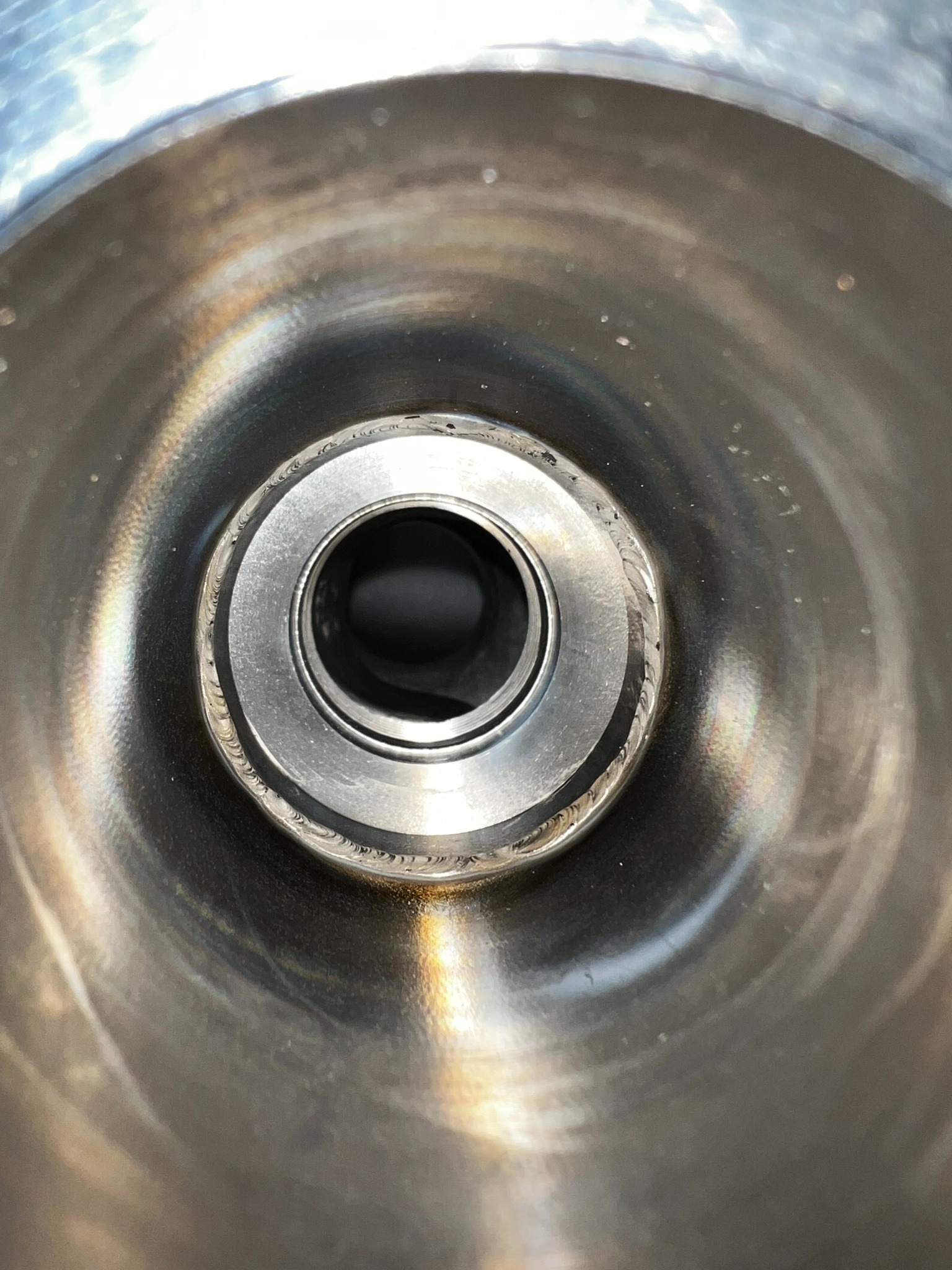 Wnętrze metalowej rury z widocznym spawem, ukazujące precyzję łączenia elementów. Widoczne ślady obróbki i charakterystyczne przebarwienia termiczne.