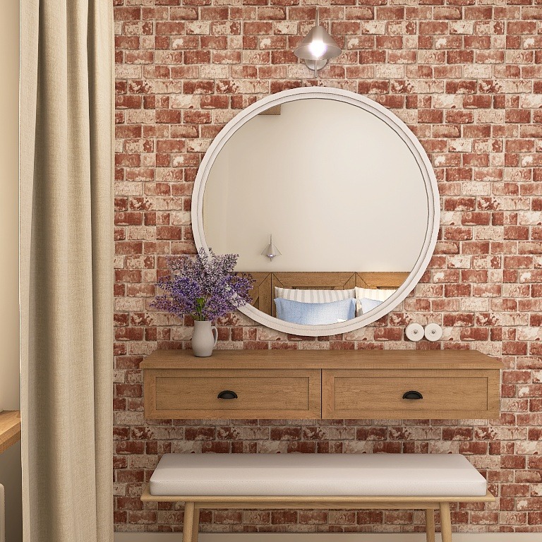 Rustykalna łazienka z ceglaną ścianą, okrągłym lustrem i drewnianą konsolą. W lustrze odbija się sypialnia. Bukiet lawendy w wazonie dodaje uroku.