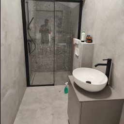 Cezary Toruński - Nowoczesna łazienka z kabiną prysznicową typu walk-in z czarną ramą, umywalką nablatową na szarej szafce i szarą glazurą na ścianach. Widoczne akcesoria łazienkowe.