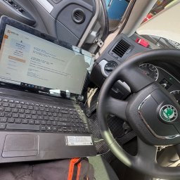 Mechanika Samochodowa SZYNALIK Damian Szynalik - Diagnostyka komputerowa Skoda Octavia: laptop z uruchomionym programem diagnostycznym podłączony do samochodu. Widoczna deska rozdzielcza i kierownica.