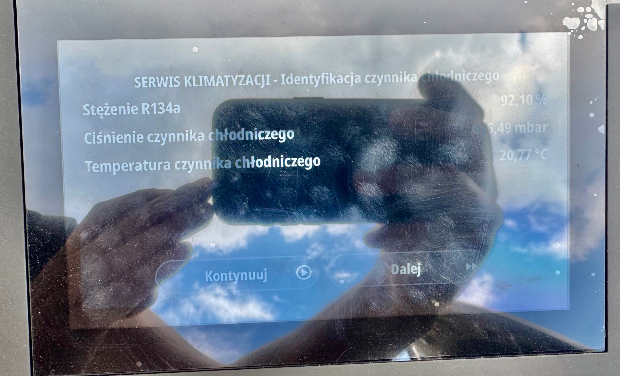 Ekran urządzenia do serwisu klimatyzacji z widocznymi parametrami czynnika chłodniczego: stężenie R134a, ciśnienie i temperatura. Widoczne opcje 'Kontynuuj' i 'Dalej'.