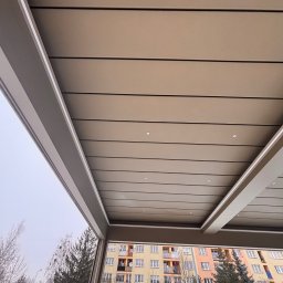 Adrian Durak - Nowoczesna zabudowa balkonu z oświetleniem LED w Gózdek, widok z dołu na sufit i otoczenie budynku mieszkalnego.