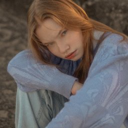 fredieme.photo - Alfred Wiśniewski - Portret młodej kobiety o rudych włosach, ubranej w błękitny sweter, siedzącej na tle szarej, teksturowanej powierzchni. Delikatne światło podkreśla rysy twarzy.