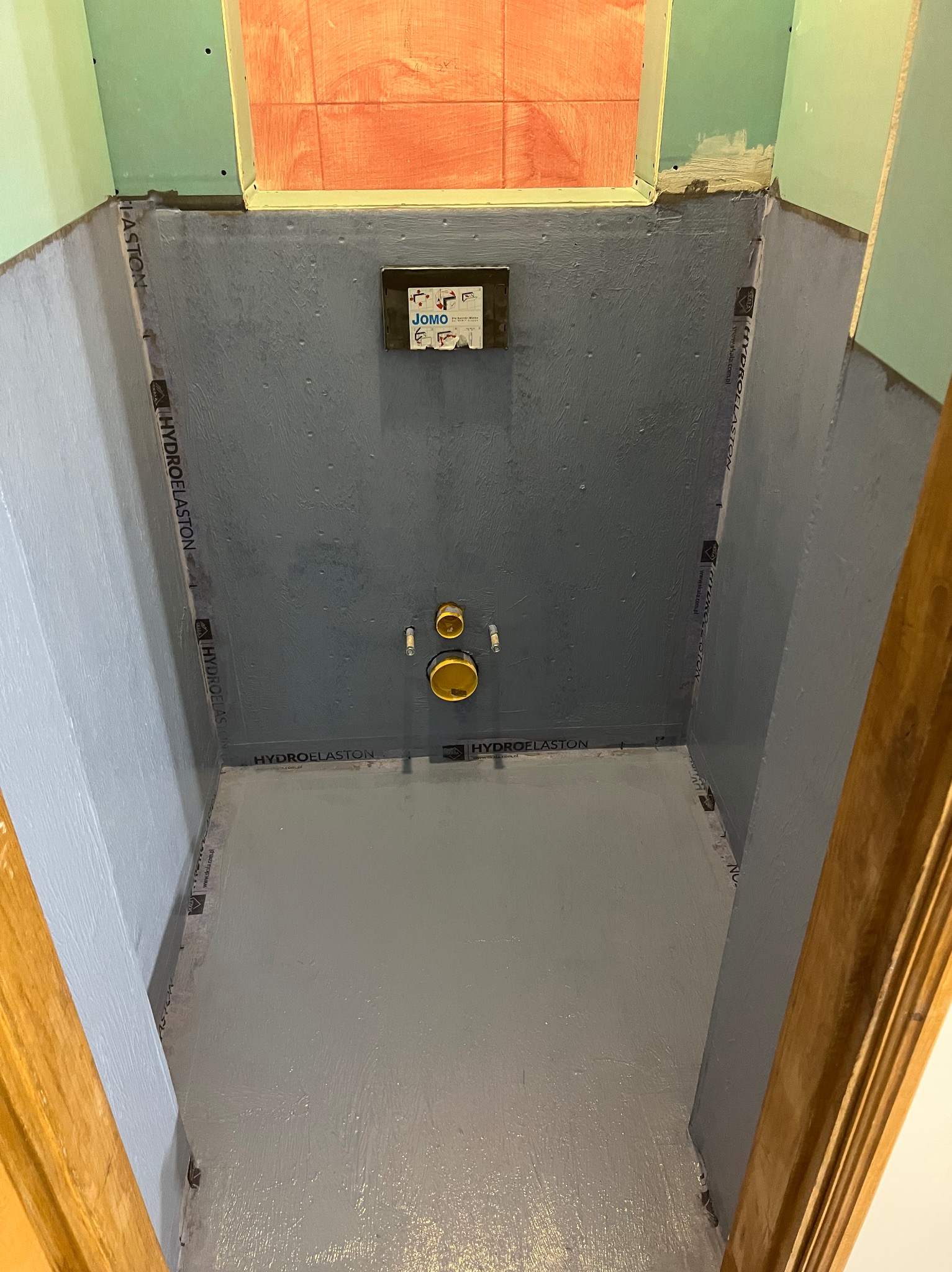 Przygotowanie do hydroizolacji w łazience w Skoczowie. Widoczne zabezpieczone ściany i podłoga, gotowe do dalszych prac wykończeniowych. Detal: taśma uszczelniająca.