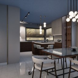 Wymarzony Dom Sp. z o.o. - Nowoczesna kuchnia z wyspą i jadalnią, oświetlona wiszącymi lampami. Minimalistyczny design, jasne kolory, duże okno z widokiem na zieleń. Eleganckie krzesła i stół.