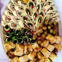 Zajazd Rowerowy Nawsie Mariusz Witek - Elegancka taca z tortillami, koreczkami i pasztecikami, dekorowana pomarańczami i sałatą, idealna na catering firmowy lub świąteczny.