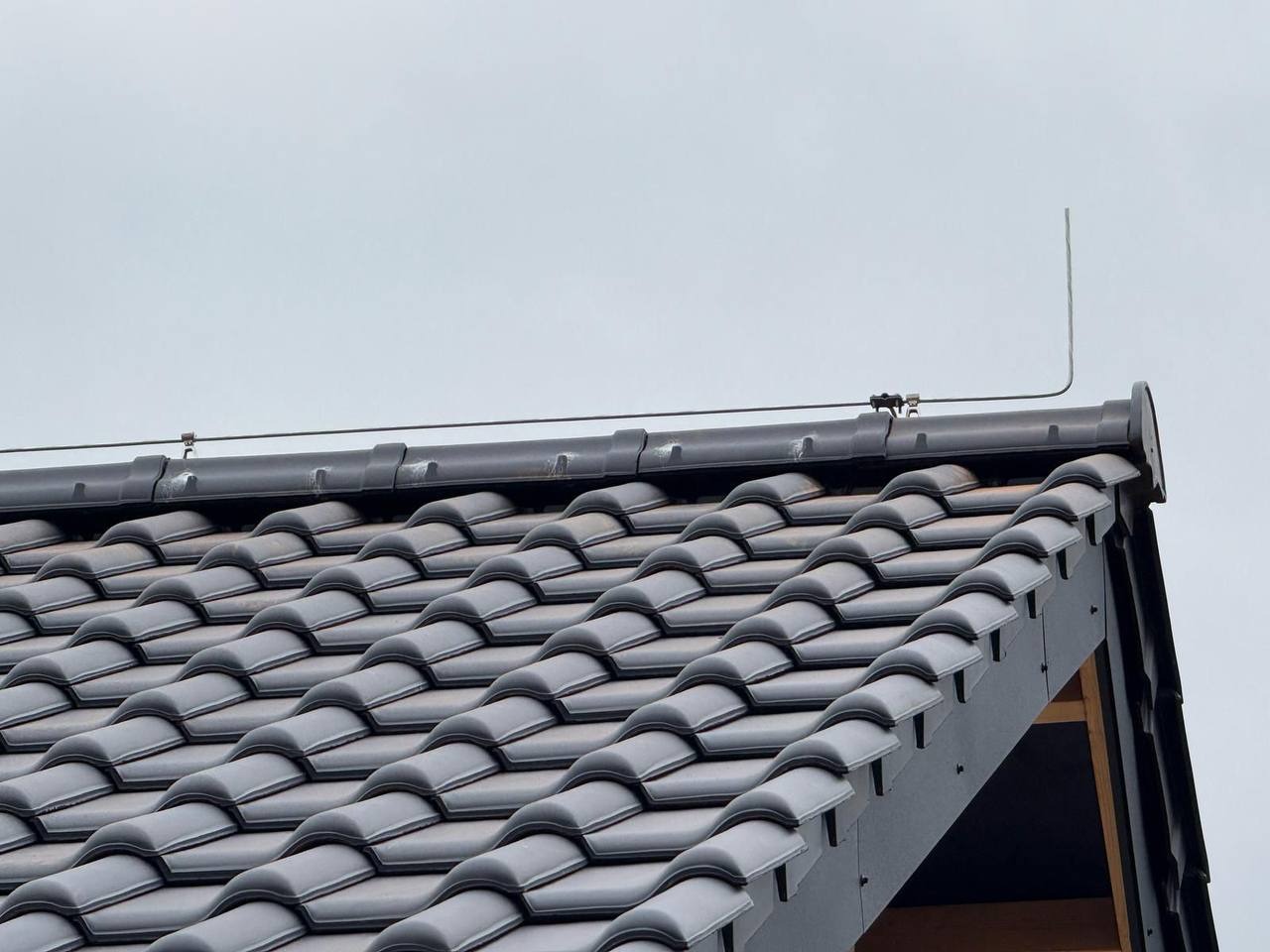 Czarny dach z dachówki ceramicznej z systemem odgromowym, widoczny z dołu w Strzegomiu. Precyzyjne ułożenie, estetyczne wykończenie.