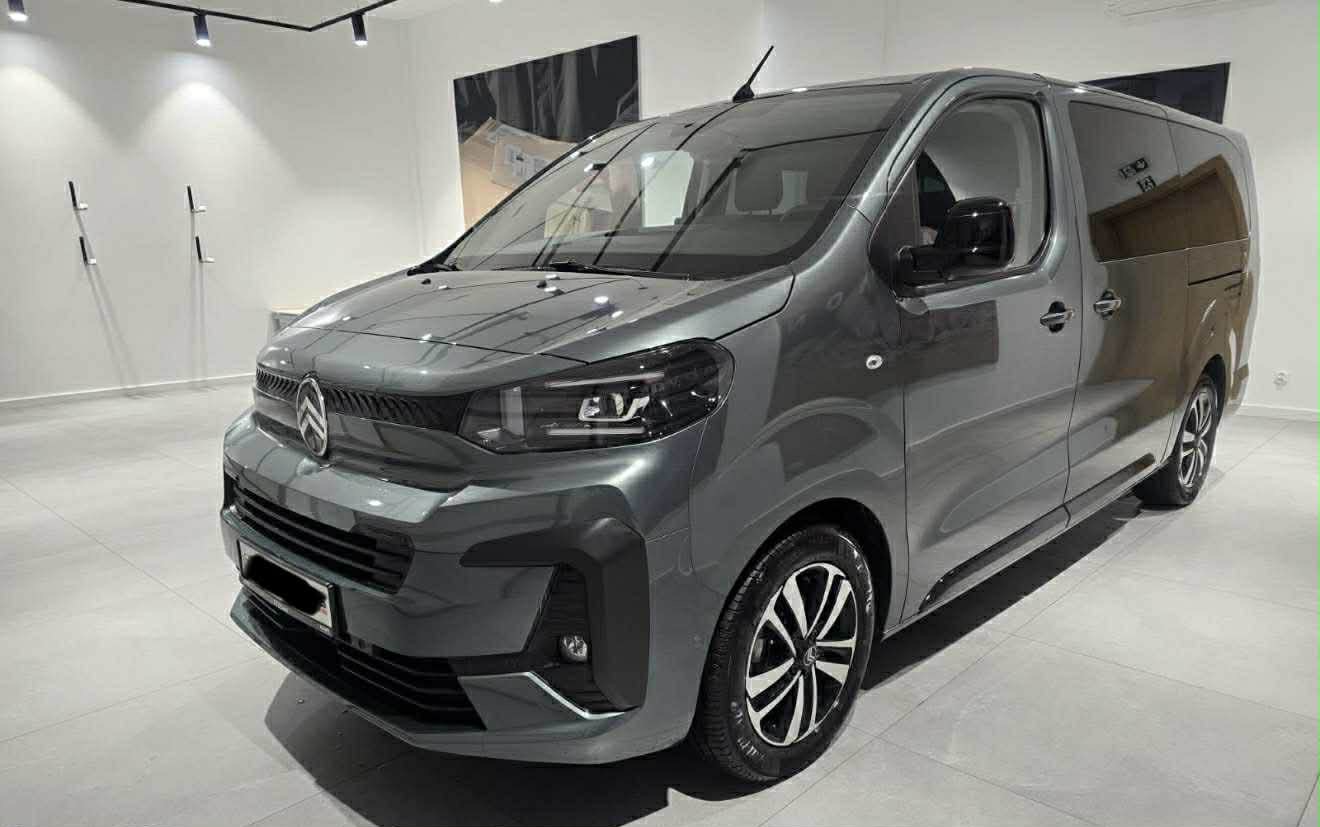 Szary, nowoczesny bus Citroen z aluminiowymi felgami, prezentowany w jasnym, minimalistycznym salonie z oświetleniem punktowym i stonowanym tłem.