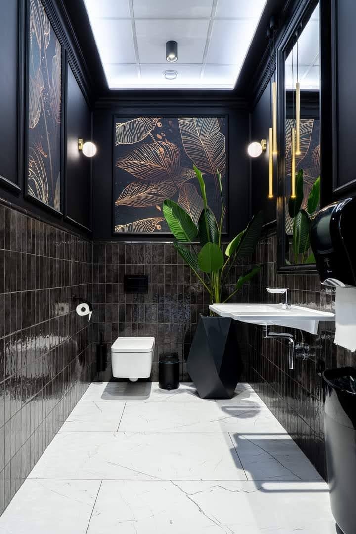 Elegancka, wąska łazienka w ciemnych tonacjach z białymi akcentami. Ciemne płytki na ścianach, biała marmurowa podłoga, designerska umywalka i lustro z wiszącymi lampami.