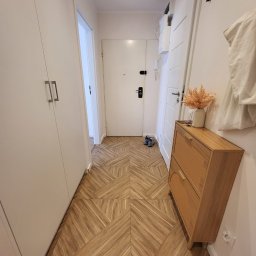 Zakład Produkcyjno - Handlowy MIKOR Andrzej Wudzki - Nowoczesny przedpokój z drewnianą podłogą w geometryczny wzór, białą szafą i komodą. Minimalistyczny design, jasne wnętrze.