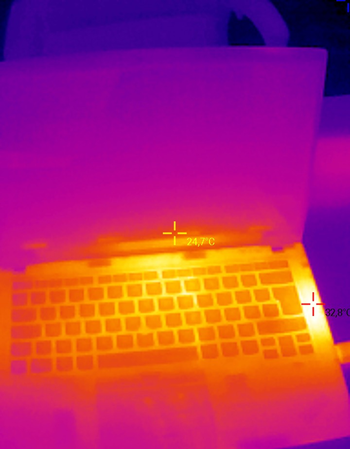 Laptop poddany termowizyjnej kontroli, ukazujący rozkład temperatur na klawiaturze i obudowie w odcieniach fioletu i pomarańczy, z zaznaczonymi punktami pomiaru temperatury.