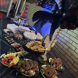 PIOTR NOWAK & CO. EVENTS - Dekoracyjny stół z fontanną czekoladową, owocami, słodyczami i piórami na przyjęciu. Elegancki catering z czarnymi balonami i złotymi akcentami.
