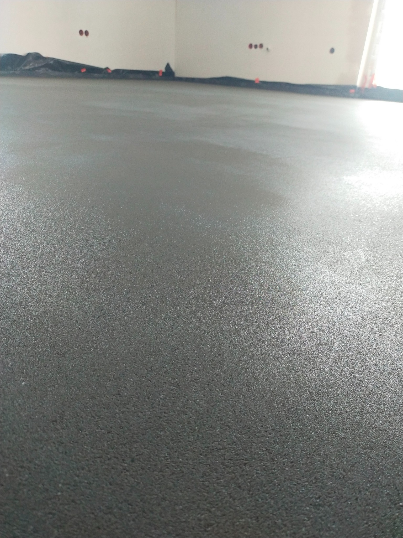 Świeżo wylana, gładka posadzka w pomieszczeniu, widoczne detale powierzchni. Realizacja w Tarnowcu.