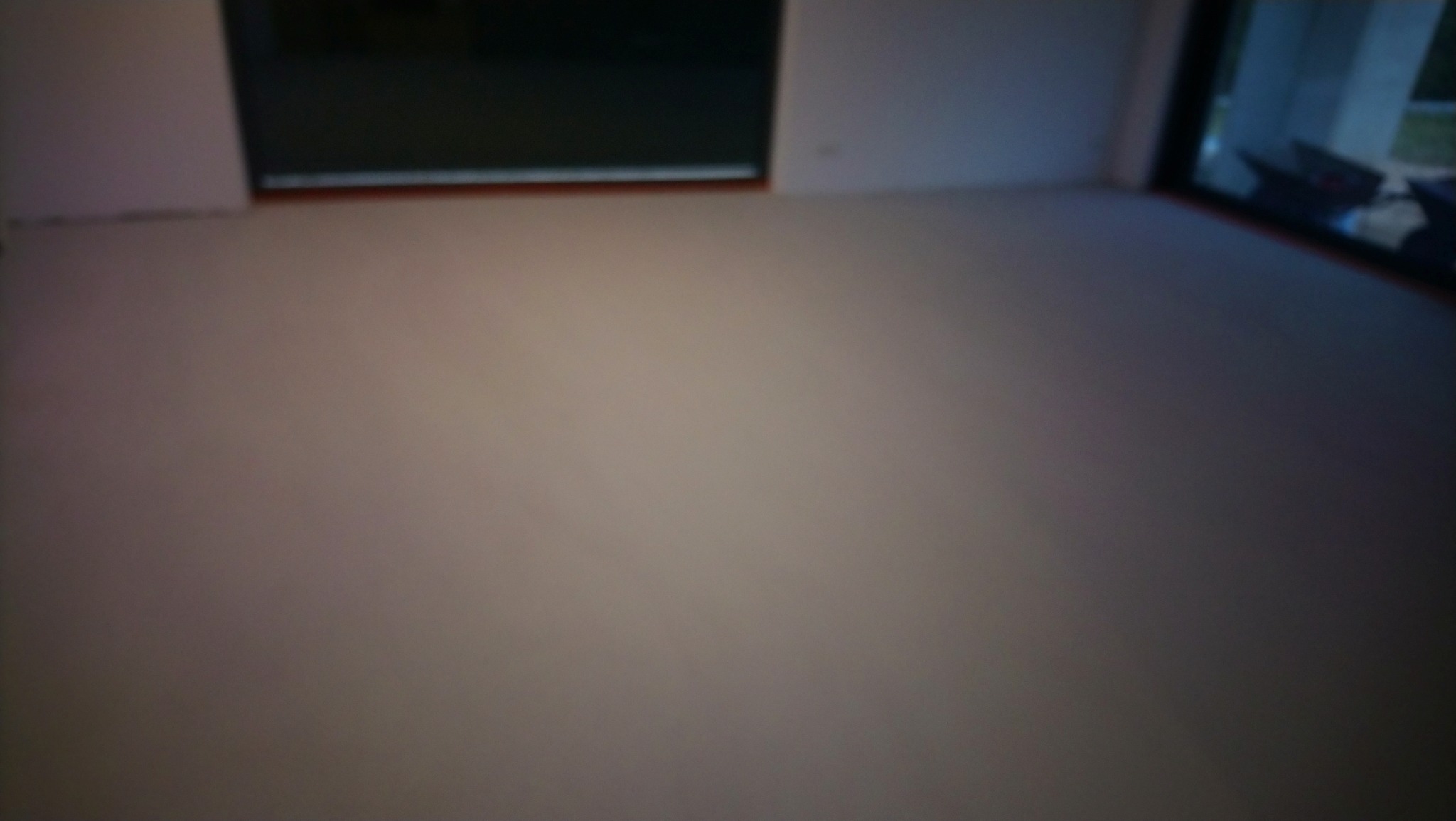 Jasna, gładka posadzka w pokoju z dużymi oknami. Minimalistyczne wnętrze z widoczną strukturą wylewki. Delikatne światło podkreśla jednolitą powierzchnię.